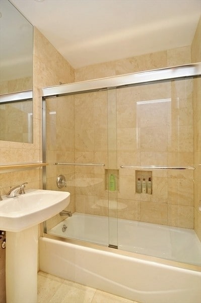 bathroom featuring tile walls, tile patterned floors, and combined bath / shower with glass door