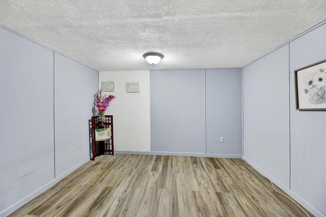 below grade area with a textured ceiling, baseboards, and wood finished floors