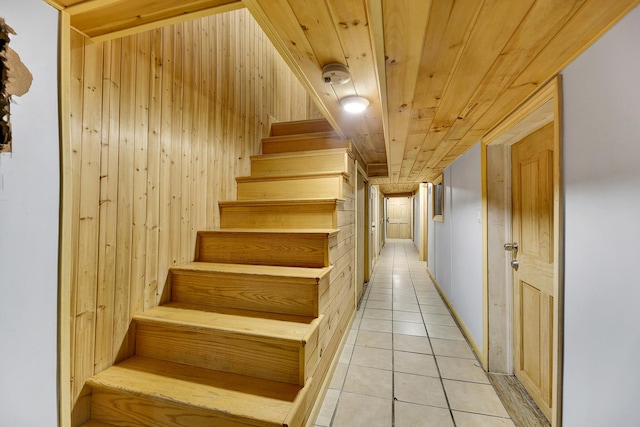 staircase with wooden walls, wood ceiling, and tile patterned flooring