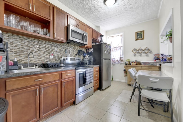 kitchen with decorative backsplash, brown cabinetry, appliances with stainless steel finishes, a sink, and an ornate ceiling