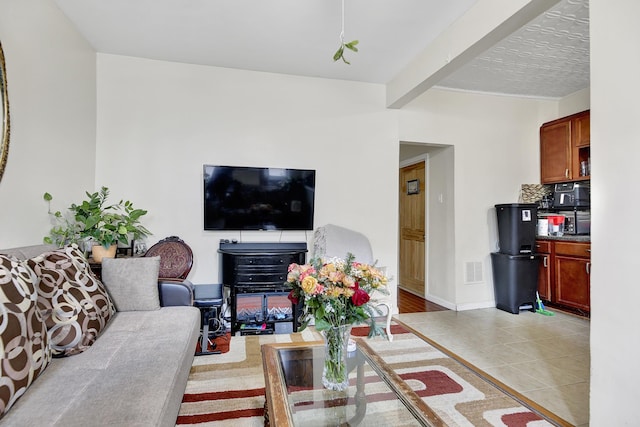 living room with visible vents, baseboards, light tile patterned floors, and beamed ceiling