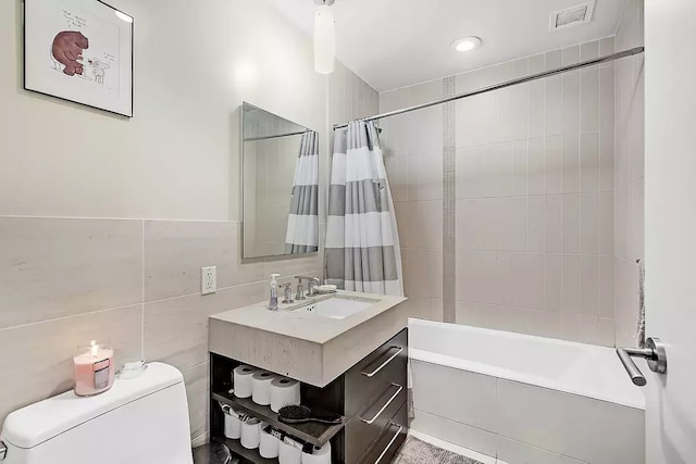 full bathroom featuring tile walls, toilet, vanity, and shower / bathtub combination with curtain