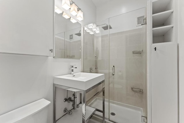 bathroom with sink, toilet, and a shower with door