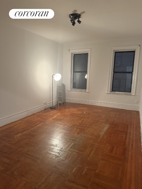 empty room with radiator and dark parquet flooring