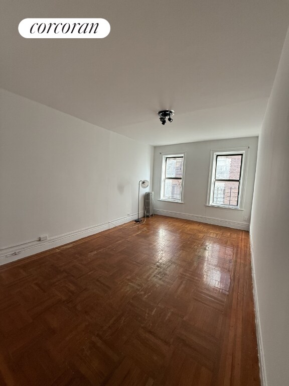 spare room with radiator and dark parquet floors