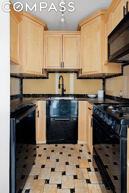 kitchen with dark stone counters, sink, light brown cabinets, and black appliances