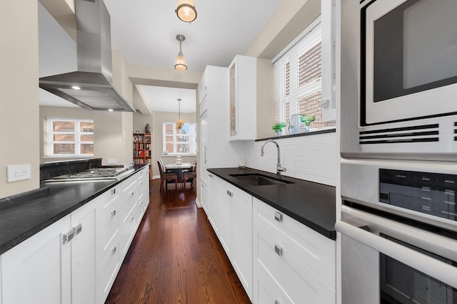 kitchen featuring a sink, dark countertops, dark wood-style floors, ventilation hood, and appliances with stainless steel finishes