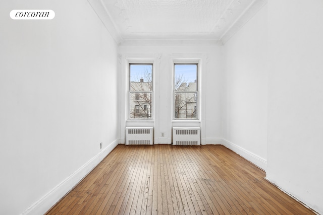 unfurnished room with baseboards, hardwood / wood-style flooring, and radiator