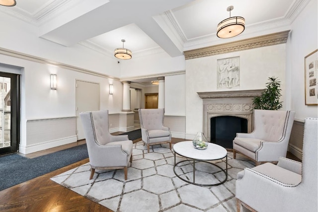 living area featuring wainscoting, ornamental molding, a fireplace, and decorative columns