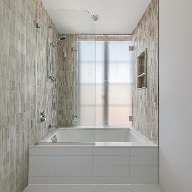 bathroom with tile walls and tiled shower / bath