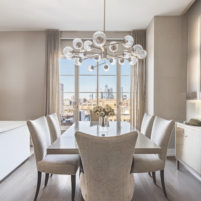 dining space with a chandelier, a skyline view, and wood finished floors