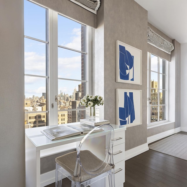 office area with dark wood finished floors, baseboards, and a city view