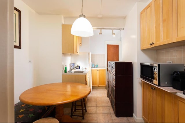 kitchen with hanging light fixtures, decorative backsplash, sink, and light brown cabinetry