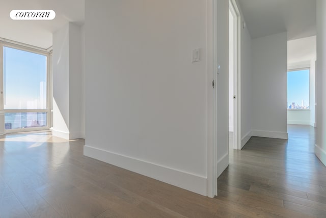 hallway with dark wood finished floors, visible vents, and baseboards