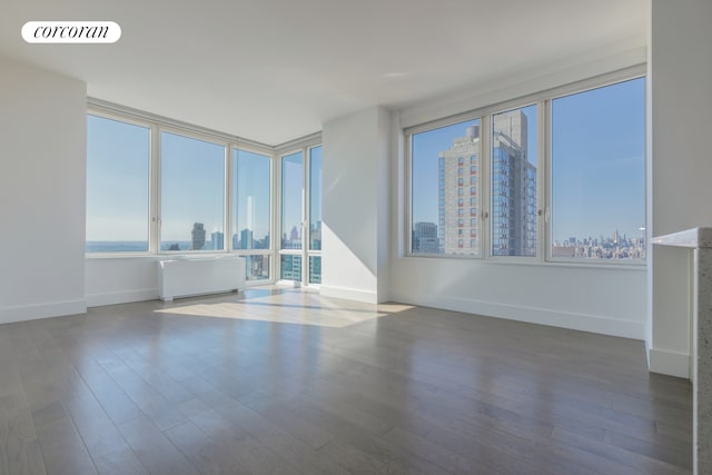 388 Bridge St Unit 43H, New York City, NY 11201 - empty room with visible vents, a city view, wood finished floors, radiator heating unit, and baseboards