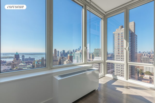 sunroom / solarium with radiator heating unit, a water view, and a city view