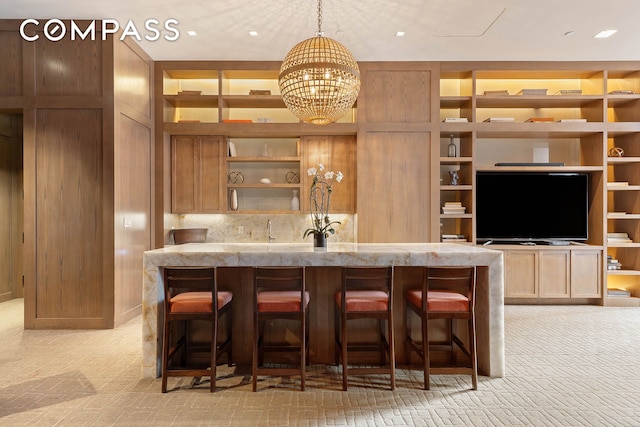 kitchen with open shelves, a kitchen bar, and light stone countertops