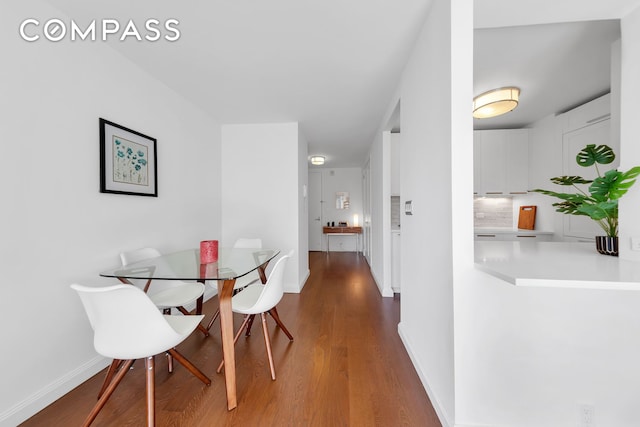 dining space with baseboards and dark wood finished floors