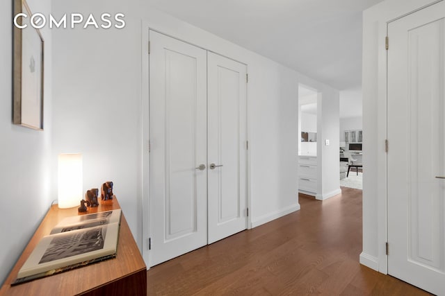 corridor featuring dark wood-type flooring and baseboards