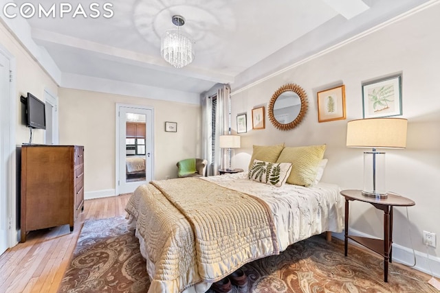 bedroom with beam ceiling, wood-type flooring, and a chandelier