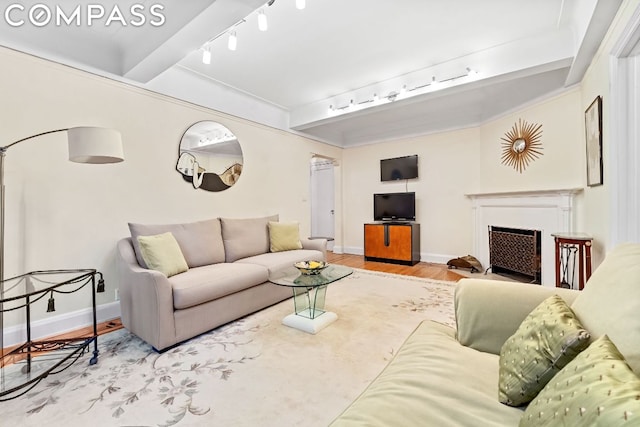 living room featuring track lighting, beamed ceiling, and light wood-type flooring