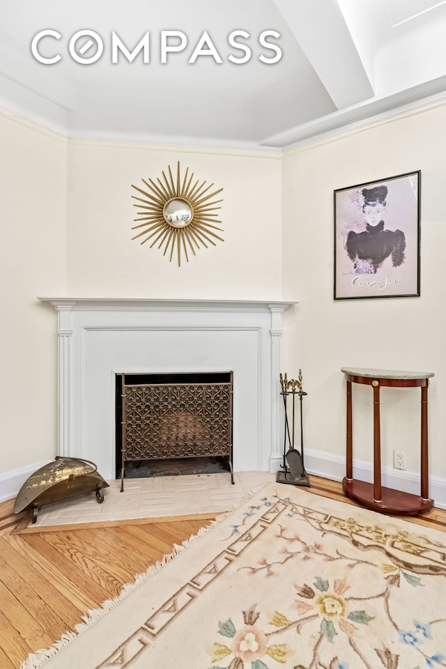 room details with a fireplace with flush hearth, wood finished floors, baseboards, and ornamental molding