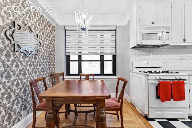 dining space with a notable chandelier, light wood-style floors, and baseboards