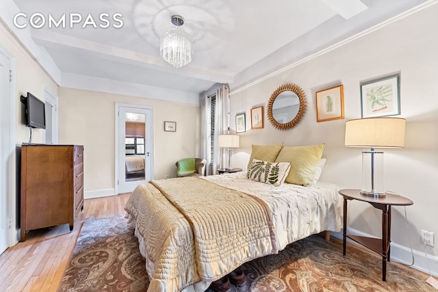 bedroom with beamed ceiling, an inviting chandelier, baseboards, and hardwood / wood-style flooring