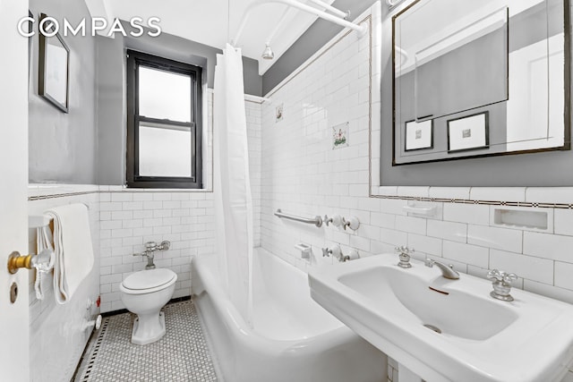 bathroom featuring tile patterned flooring, toilet, shower / bath combo, tile walls, and a sink