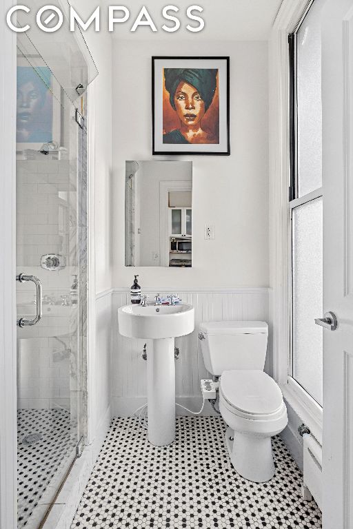 bathroom with toilet, tile patterned flooring, sink, and a shower with shower door