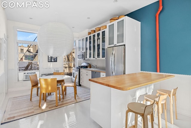 kitchen featuring white cabinets, appliances with stainless steel finishes, a kitchen island, sink, and a breakfast bar area