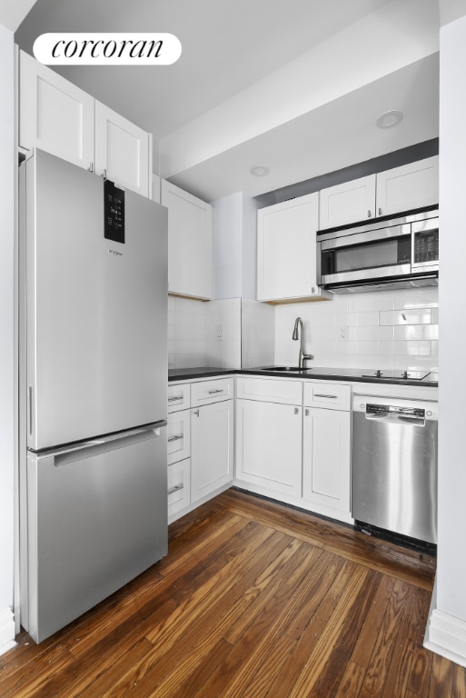 kitchen featuring dark wood-type flooring, white cabinets, stainless steel appliances, and tasteful backsplash