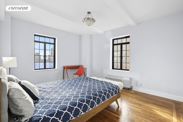 bedroom featuring beamed ceiling, hardwood / wood-style flooring, and a wall unit AC