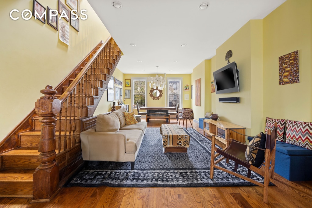 living area with stairway, recessed lighting, wood finished floors, and a chandelier