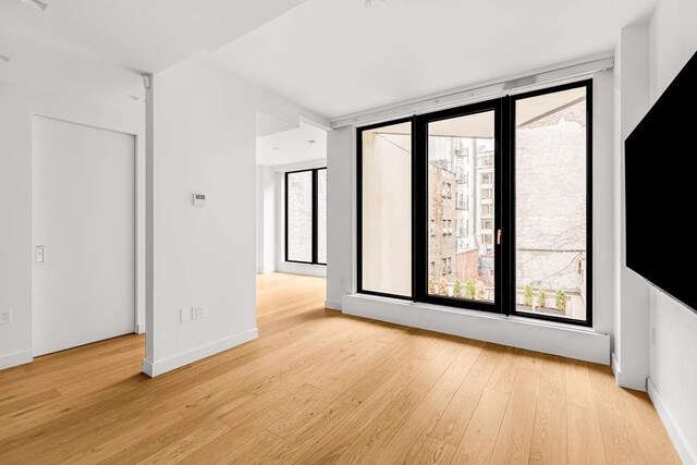 empty room with hardwood / wood-style flooring and a healthy amount of sunlight