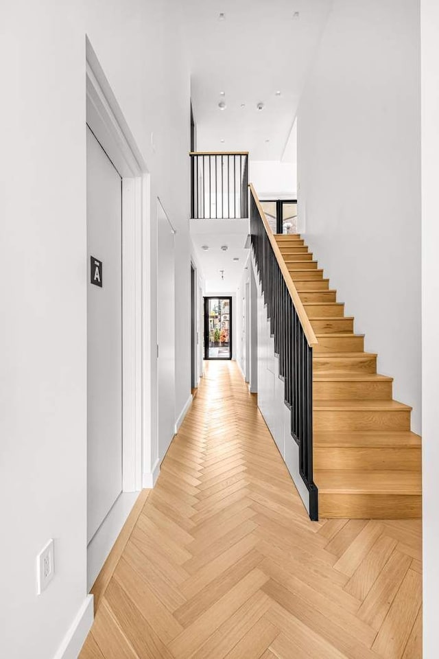 hallway with baseboards, a high ceiling, and stairway