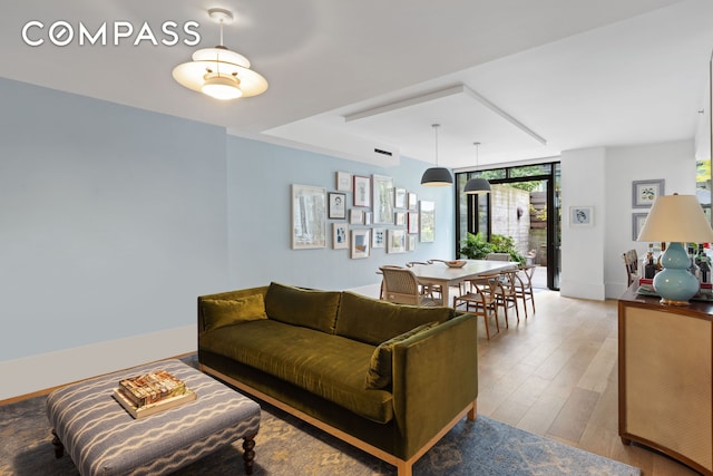 living area featuring a wall of windows, baseboards, and light wood finished floors