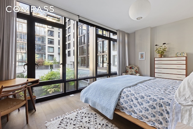 bedroom featuring access to outside, a wall of windows, and wood finished floors