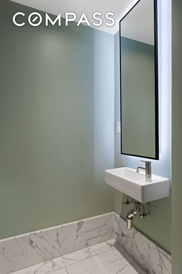 bathroom featuring marble finish floor and a sink