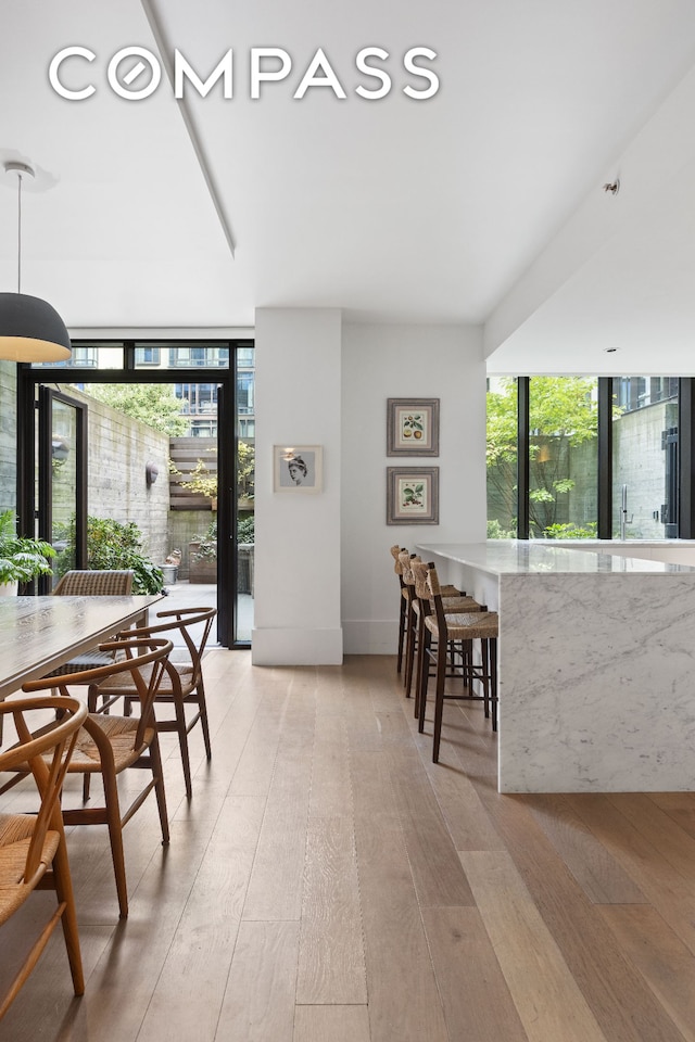 dining space with light wood finished floors and a wall of windows