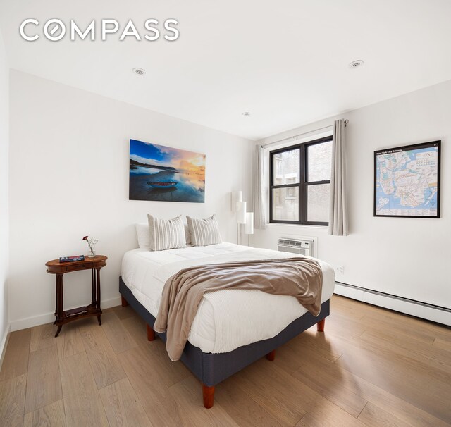 bedroom featuring hardwood / wood-style flooring, a baseboard radiator, and a wall mounted AC