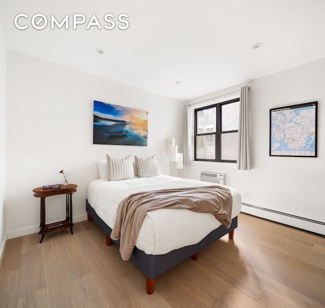 bedroom featuring baseboards, a baseboard heating unit, and light wood-style floors