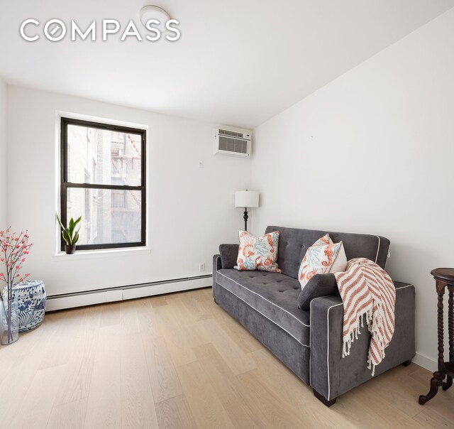 living room featuring baseboard heating, hardwood / wood-style flooring, and a wall mounted air conditioner