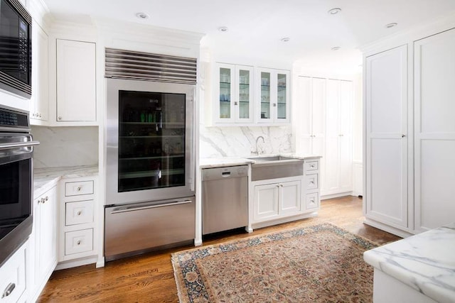 kitchen with appliances with stainless steel finishes, dark hardwood / wood-style flooring, white cabinets, light stone counters, and sink