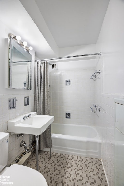 full bathroom featuring sink, tile walls, tile patterned flooring, toilet, and shower / bathtub combination with curtain