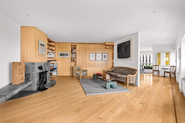living room featuring a fireplace, wooden walls, and wood finished floors