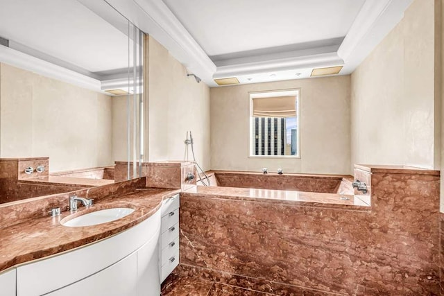 bathroom with crown molding, tiled bath, vanity, and a tray ceiling