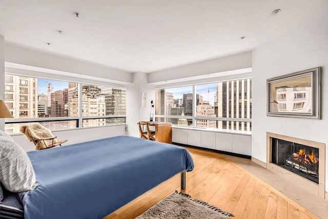 bedroom featuring a fireplace with flush hearth, a view of city, and hardwood / wood-style floors