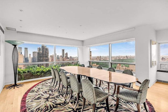 dining area featuring a city view, a healthy amount of sunlight, and light wood-style floors