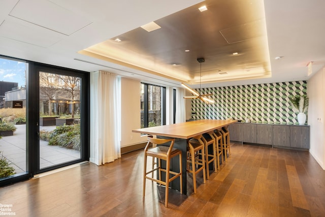 202 Broome St Unit 7L, New York City, NY 10002 - dining room featuring wallpapered walls, a raised ceiling, dark wood finished floors, expansive windows, and an accent wall